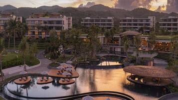 Ein Resort mit Poolbereich, Liegestühlen und Blick auf den Sonnenuntergang.