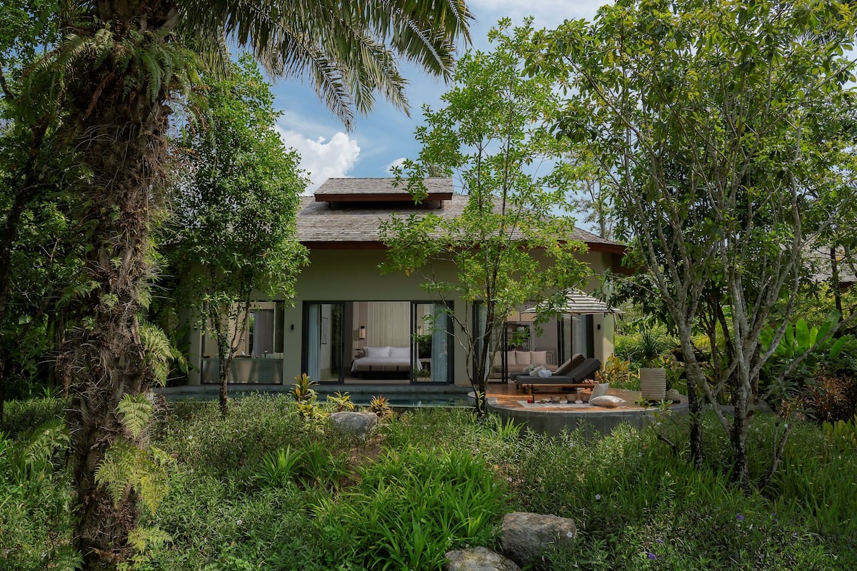 A modern house with a large glass door, a patio with a sofa, and a swimming pool.