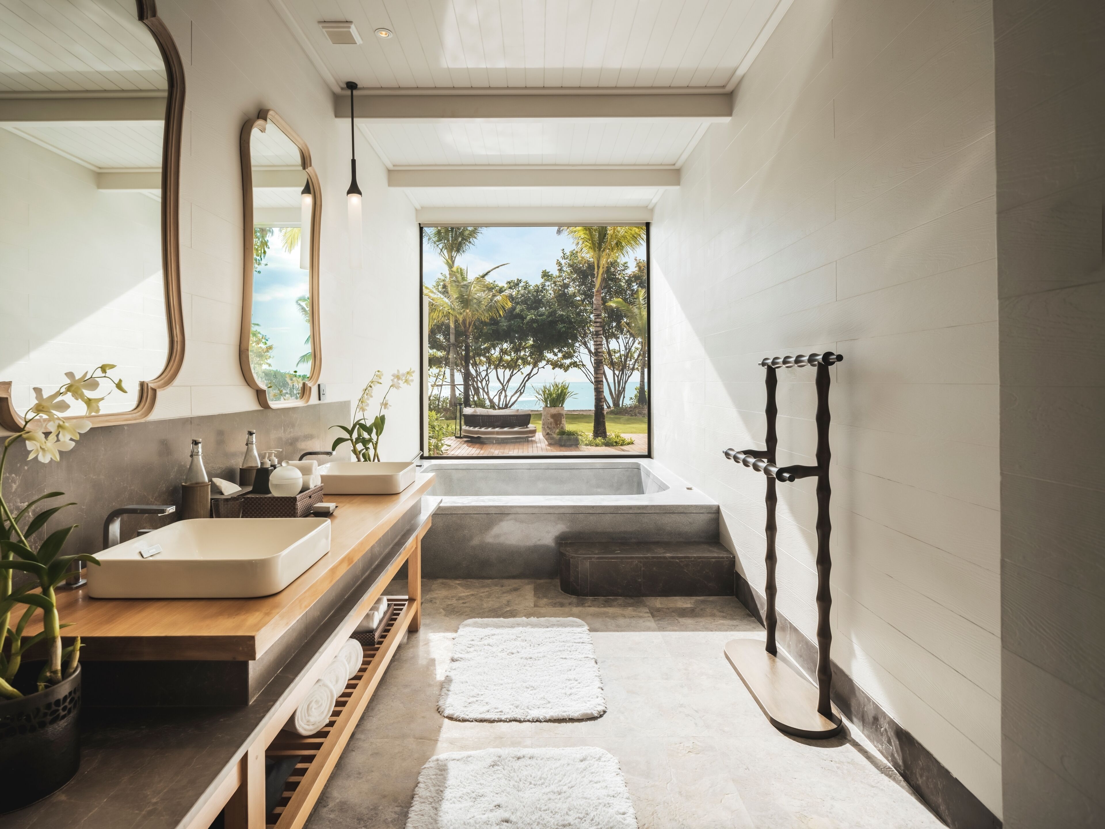 Un baño moderno con un espejo grande, una bañera y una ducha.