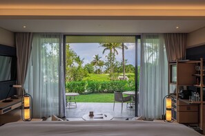 A hotel room with a large sliding glass door leading to a private outdoor area with a lawn and palm trees. - Anantara Koh Yao Yai Resort & Villas (Ko Yao)