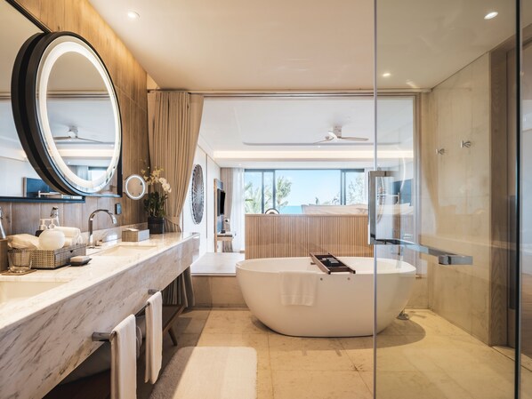 Un baño moderno con una bañera ovalada grande, un espejo redondo y un tocador con encimera de mármol.
