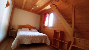 A cozy bedroom with a wooden ceiling, a bed with white bedding, a nightstand, and a window with red curtains. - Les Salamanes - 3 double bedrooms - 2 bathrooms - domaine du Grand Massif (Sixt-Fer-à-Cheval)