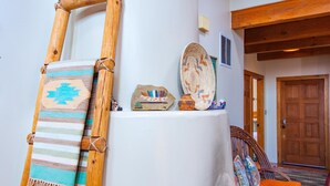 Ein Zimmer mit einer Holzleiter, einem gewebten Korb und einer gewebten Matte auf einer weißen Säule.