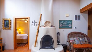 Ein gemütliches Zimmer mit Kamin, einem Korbstuhl und einem Bett.
