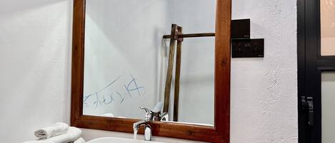 A bathroom with a wooden-framed mirror, a white sink, and a towel rack with towels.