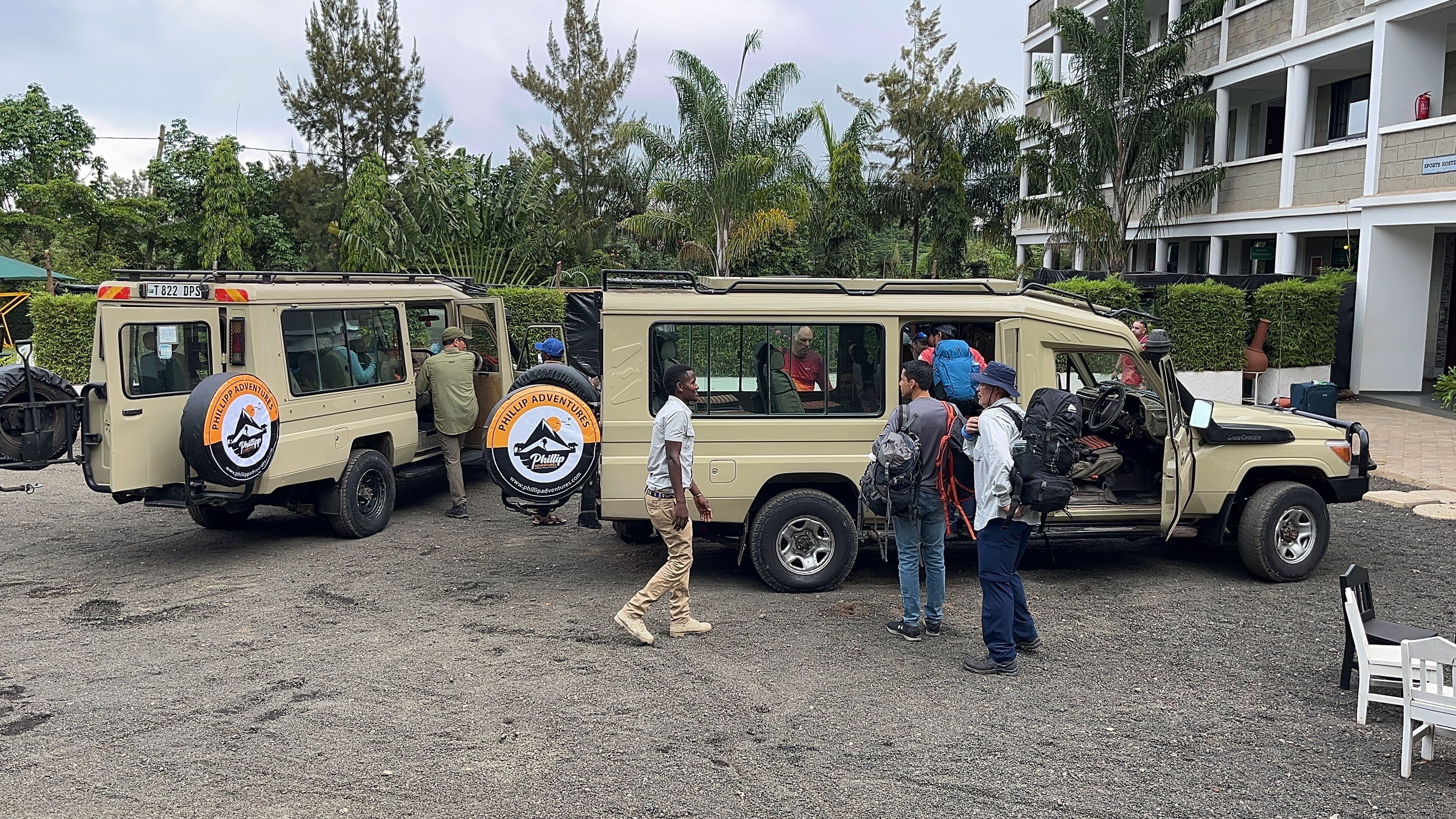 Un groupe de personnes monte à bord d’un véhicule tout-terrain beige orné du logo de « Philipp Adventures ».