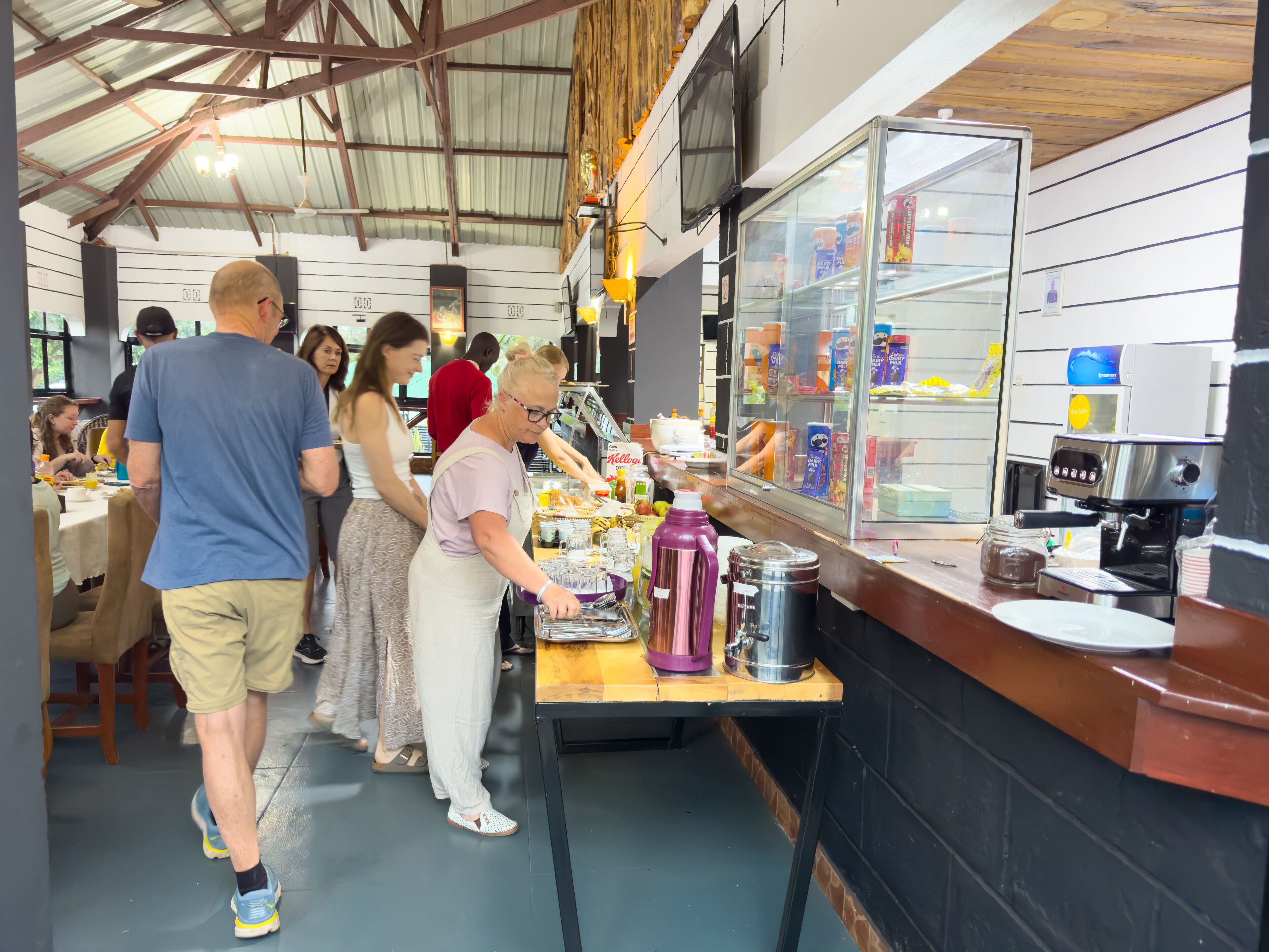 Una cafetería con mostrador, máquina de café y diferentes productos alimenticios.