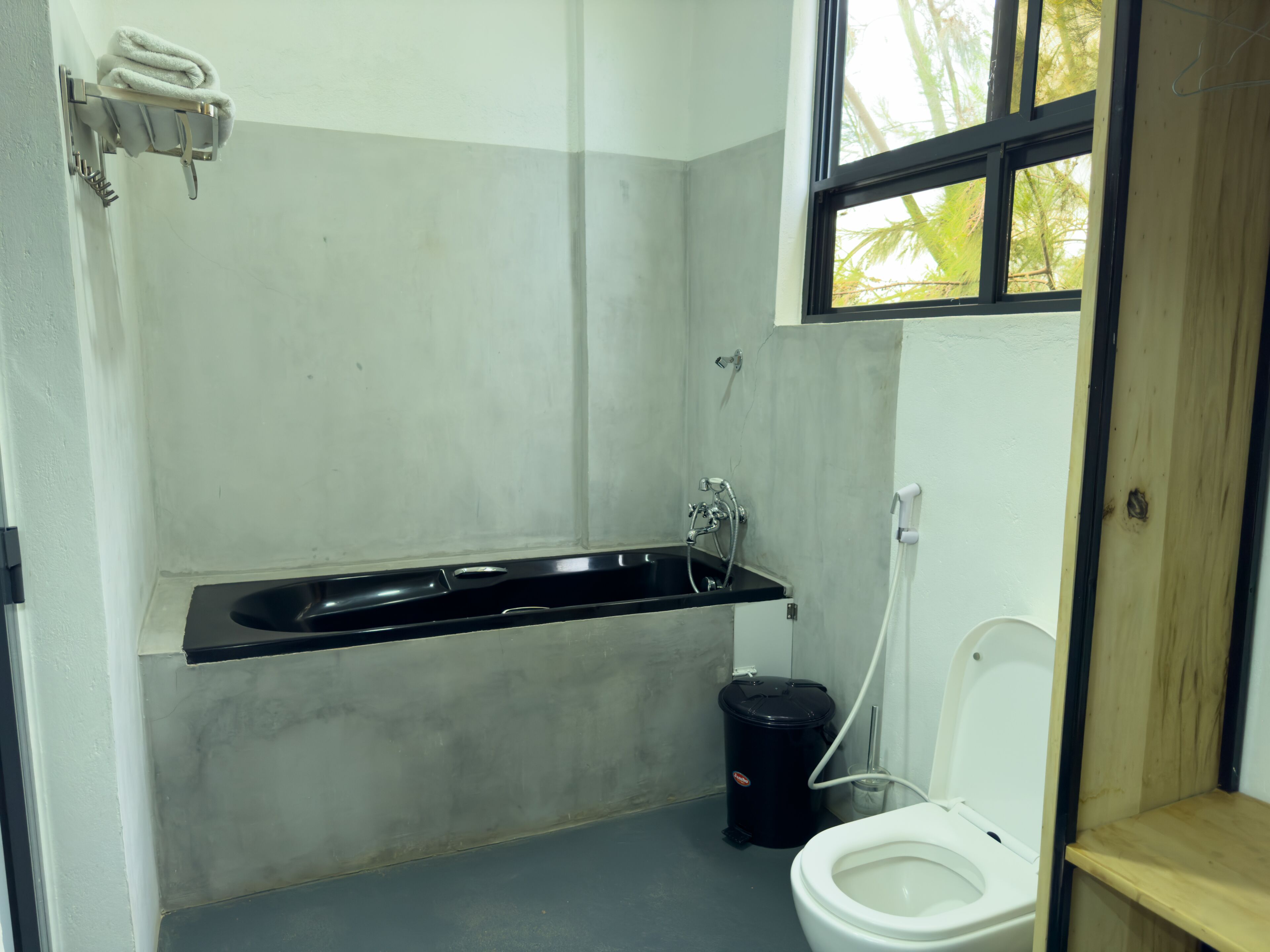 A small bathroom with a black sink, a white toilet, and a black trash bin.