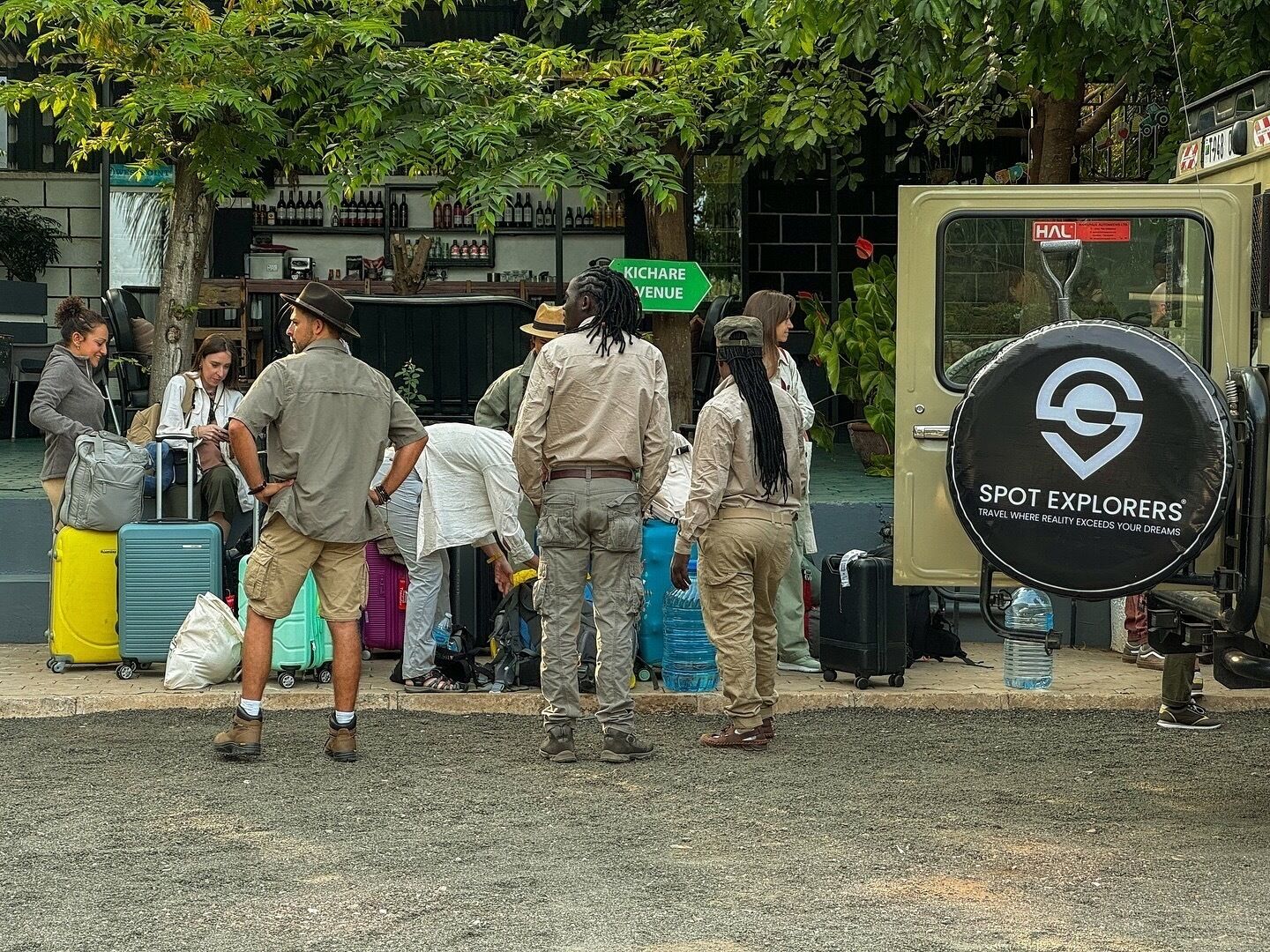 A group of people with luggage near a vehicle with a sign reading "SPOT EXPLORERS".