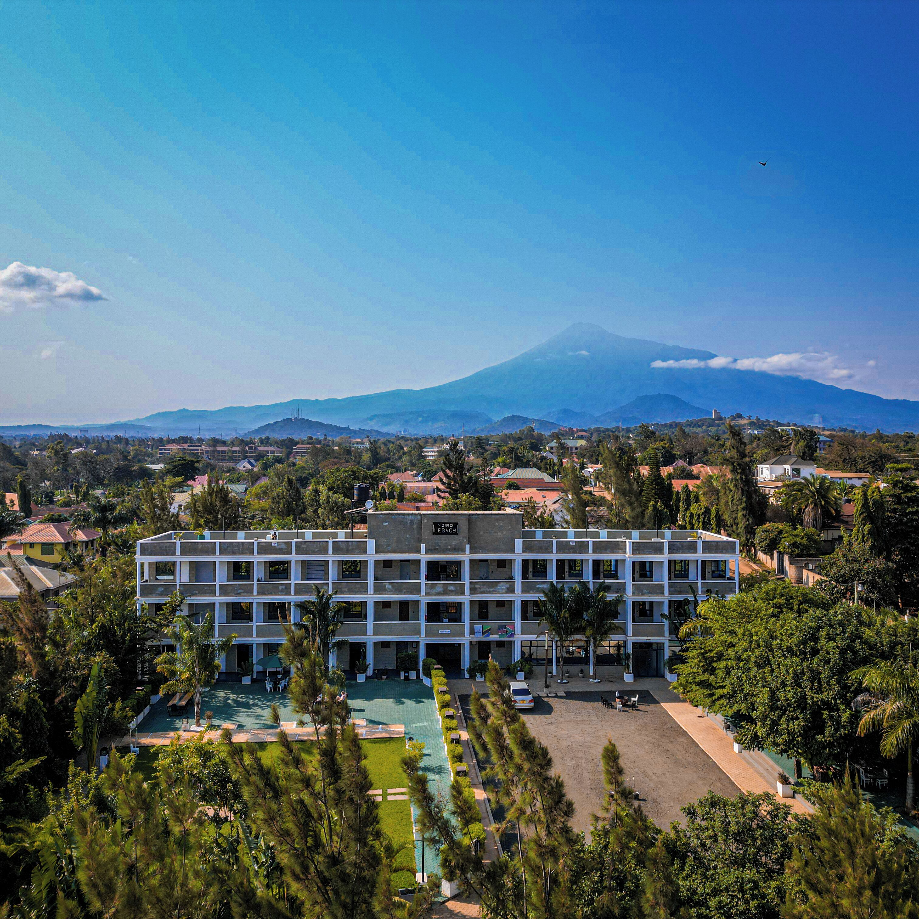 A multi-story hotel with a pool area and a view of a mountain.