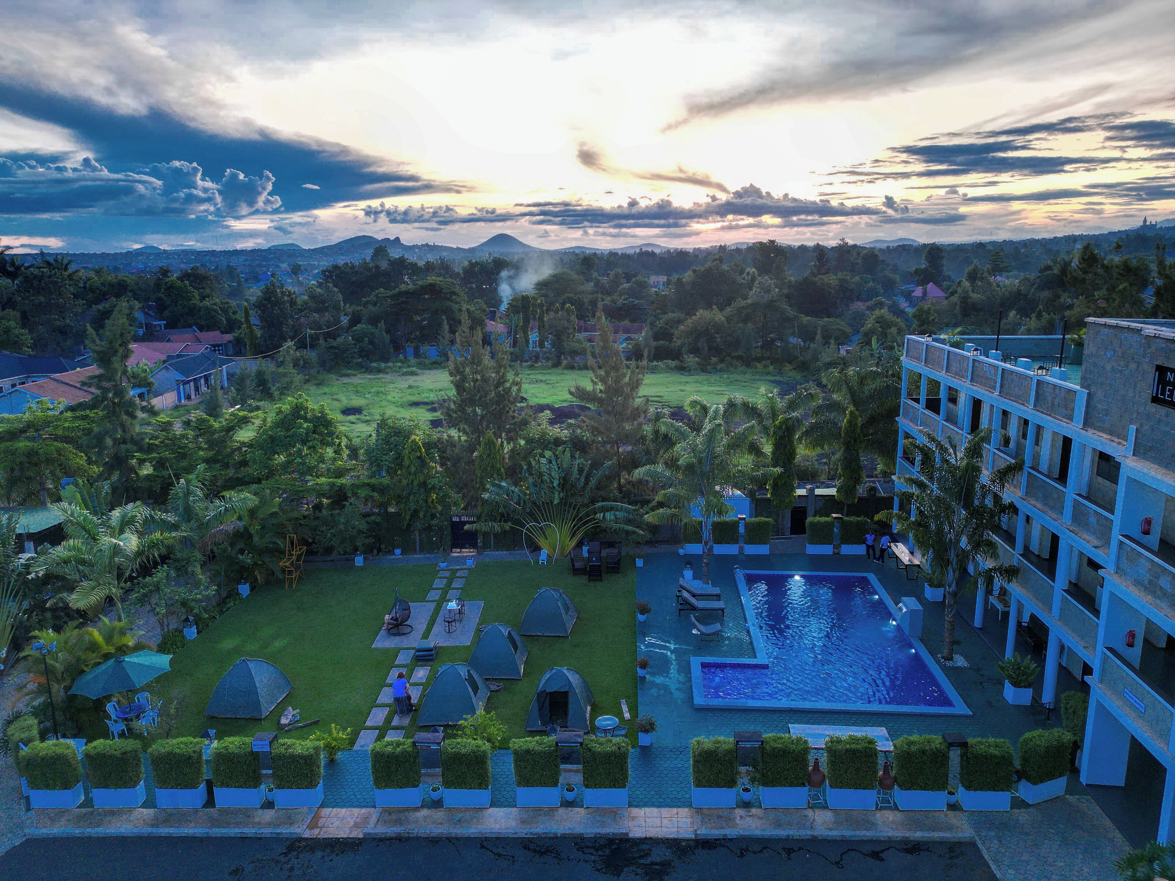 A resort with a swimming pool, multiple tents, and lush greenery.