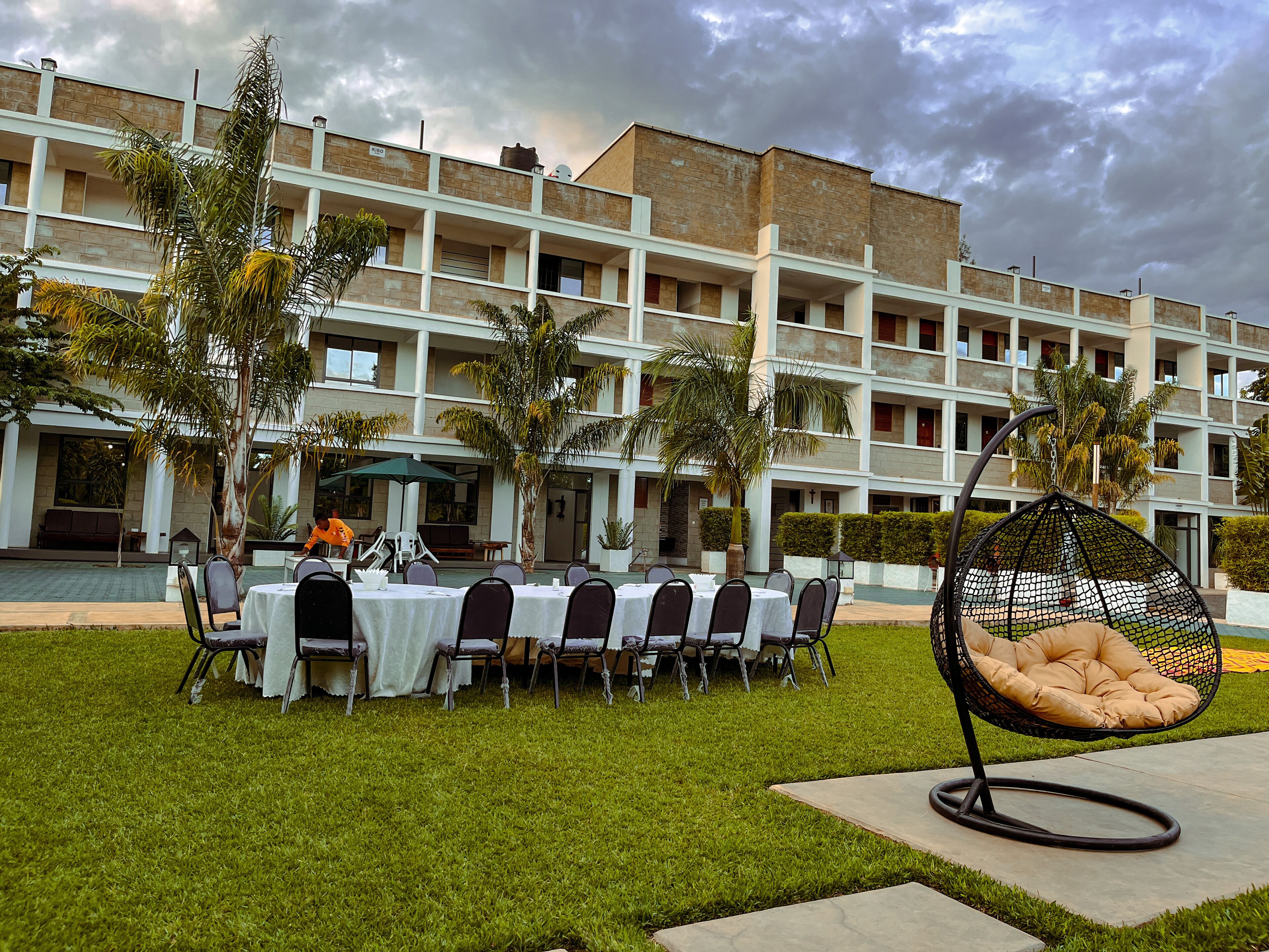 A hotel courtyard with outdoor seating, palm trees, and a building with multiple balconies.