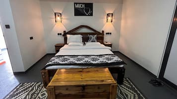 Ein ordentlich eingerichtetes Schlafzimmer mit einem Bett, zwei Nachttischen, einer hölzernen Bank und einem an der Wand befestigten Schild.