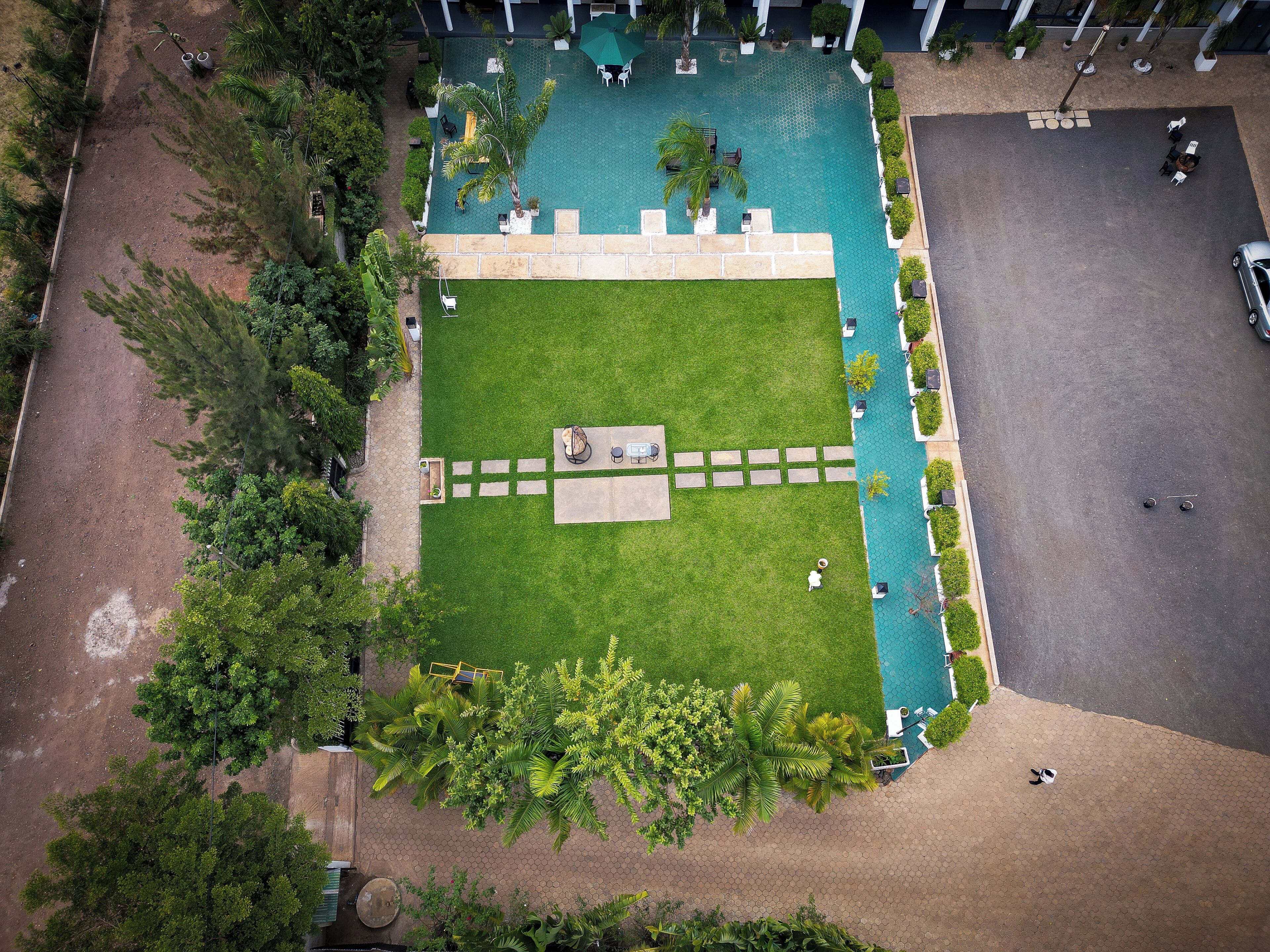 An aerial view of a hotel courtyard with a swimming pool, seating areas, and surrounding greenery.