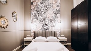 A modern bedroom with a large bed, two bedside tables, a wardrobe, and a wall with a tropical leaf pattern. - Native Apartments Paulińska 20 (Kraków)