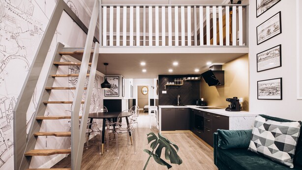 A modern interior with a staircase, dining area, kitchen, and living space. - Native Apartments Paulińska 20 (Kraków)