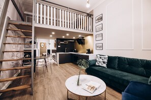 En moderne lejlighed med soveværelse på loftet, spiseplads og køkken.