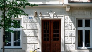 A building with a large wooden double door, a bicycle parked in front, and a tree to the left. - Native Apartments Paulińska 20 (Kraków)