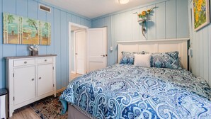 A bedroom with a bed, a dresser, a door, and a wall with a painting. - Pet Friendly - 2 Minute Walk to Beach -  Updated and Modernized Spotless Clean  (Kill Devil Hills)