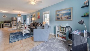 A living room with a sofa, armchairs, a coffee table, a bookshelf, and a dining area with a table and chairs. - Pet Friendly - 2 Minute Walk to Beach -  Updated and Modernized Spotless Clean  (Kill Devil Hills)