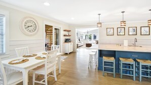 Une cuisine moderne avec un coin repas, un plancher en bois et des luminaires suspendus.