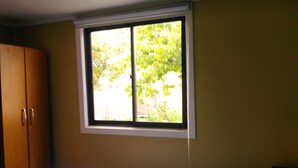 Un dormitorio con una cama, una ventana y un armario.