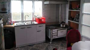 Una cocina pequeña con armarios blancos, una cesta roja y una ventana con cortinas.