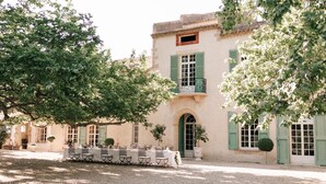 A traditional building with a stone facade, green shutters, and a courtyard with outdoor seating. - Private castle with swimming pool in Provence (Lamanon)