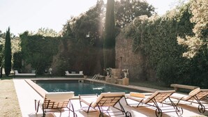 A swimming pool with lounge chairs and a stone wall in the background. - Private castle with swimming pool in Provence (Lamanon)