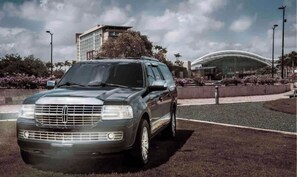 A luxury SUV parked in a landscaped area with a modern building in the background.