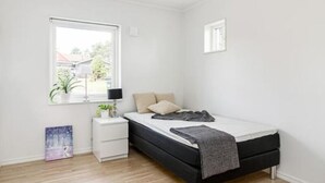 A small, bright bedroom with a single bed, a nightstand, a window with a view of the outside, and a small plant on the nightstand. - Great Stay Guest Villa 4 bedrooms (Sandviken)
