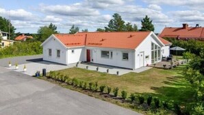 A modern two-story house with a red-tiled roof, a covered porch, and a well-maintained lawn. - Great Stay Guest Villa 4 bedrooms (Sandviken)