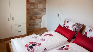 A bedroom with a bed, pillows, a wardrobe, and a stone wall.