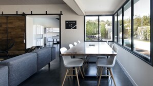 A modern hotel room with a large dining table, a sofa, and a view of the outdoors. - Comfortable villa for 10 with a pool (La Flotte)