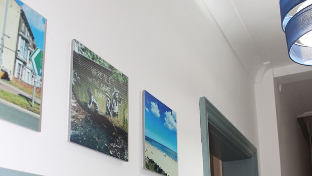A wall with three framed pictures, a heart-shaped decoration, and a light fixture. - Spacious 3 bedroom house close to the beach (Lowestoft)