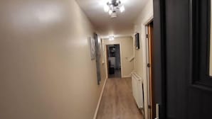 A hallway with wooden flooring, beige walls, and a ceiling light fixture. - Lovely 4 Bedroom Home With Private Parking (Grays)