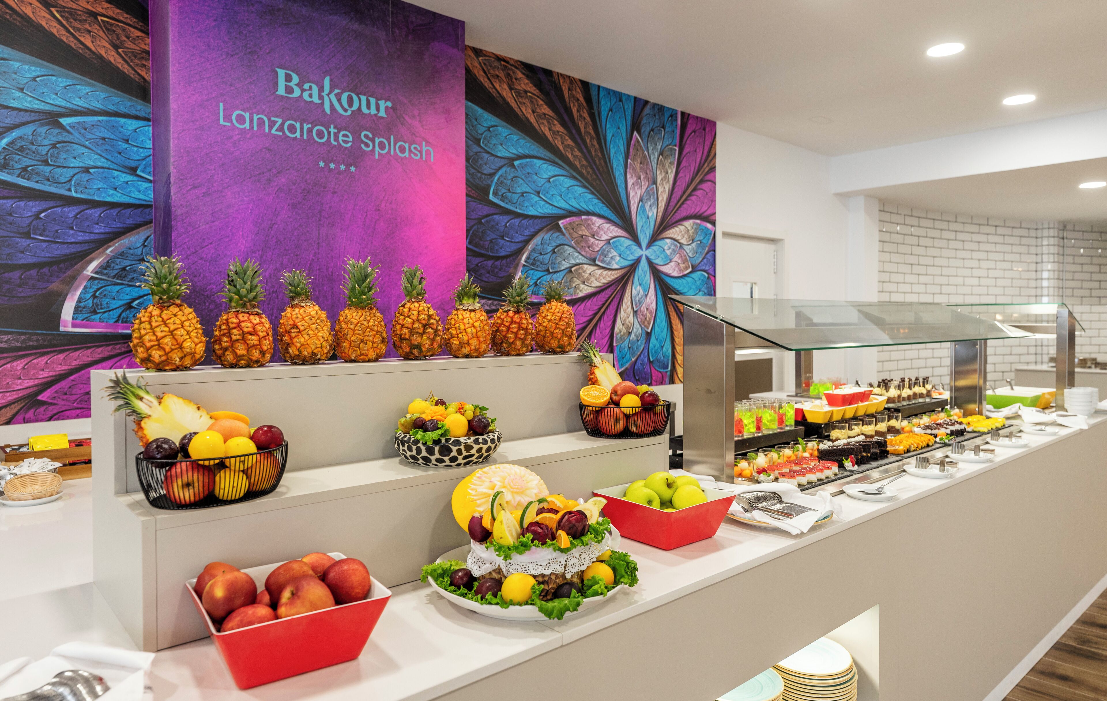 Un bufé con diversas frutas y un mural de pared colorido.