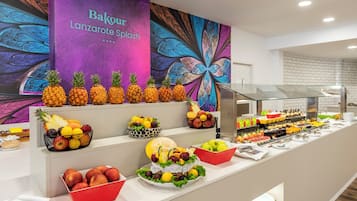 Un bufé con diversas frutas y un mural de pared colorido.