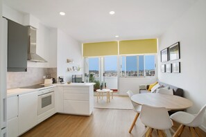 Uma cozinha moderna com armários brancos, um fogão e uma grande janela com vista para a cidade.