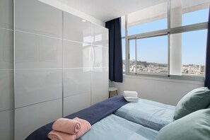 Ein Hotelzimmer mit Bett, Fenster mit Stadtblick und großem Spiegel.