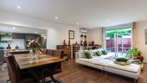A modern living room with a dining area, a sofa, and a kitchen in the background. - Villa 'Baraka' with Private Pool, Wi-Fi and Air Conditioning (SALON DE PROVENCE)