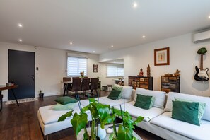 A modern living room with a sofa, dining area, and a kitchen in the background. - Villa 'Baraka' with Private Pool, Wi-Fi and Air Conditioning (SALON DE PROVENCE)