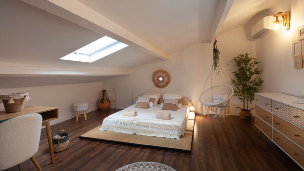 A bedroom with a skylight, a bed with white bedding, a hanging chair, a dresser, and a potted plant. - Villa 'Baraka' with Private Pool, Wi-Fi and Air Conditioning (SALON DE PROVENCE)