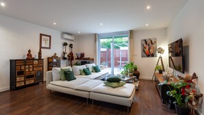 A modern living room with a sectional sofa, wooden cabinets, and a large window. - Villa 'Baraka' with Private Pool, Wi-Fi and Air Conditioning (SALON DE PROVENCE)