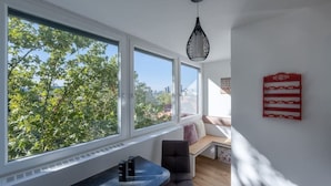 Ein modernes Zimmer mit großen Fenstern, einem schwarzen Stuhl, einem kleinen Tisch und einem roten Wanddekor.