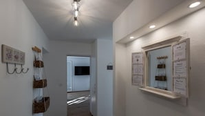 Ein Korridor mit Holzboden, einem an der Wand befestigten Fernseher und Wandkörben.