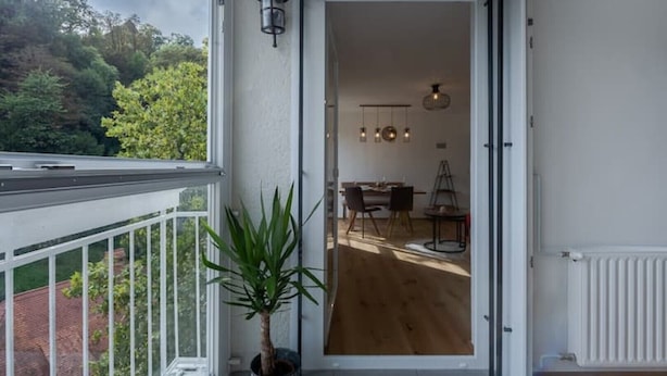 Ein Balkon mit einem Blumentopf, ein Essbereich mit Tisch und Stühlen und Blick ins Freie.