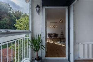 Un balcón con una planta en maceta, un área de comedor con mesa y sillas, y vistas al exterior.