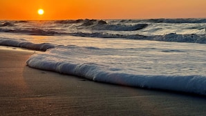 Une plage avec des vagues et un coucher de soleil.
