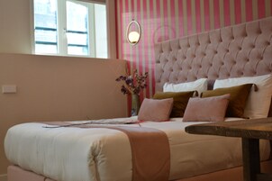 Ein Schlafzimmer mit einem gesteppten Kopfteil, einem Nachttisch und einem Fenster mit Jalousien.